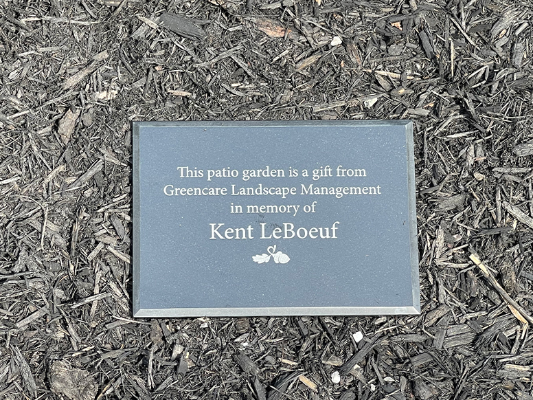 Plaque that says: This patio garden is a gift from Greencare Landscape Management in memory of Kent LeBoeuf.
